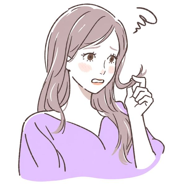 A woman looking worried at her dry, damaged hair ends